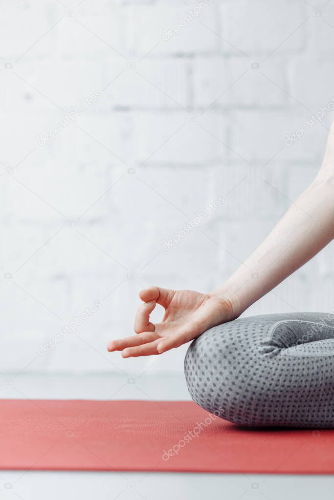 Woman practicing yoga at home. Jnana mudra close up, female, connecting the thumb and forefinger, forming a circle, palms facing upwards, harmony and concentration yoga concept, focus on right hand