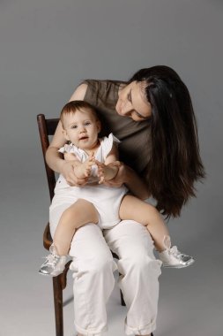 Anne ve kızını kucaklayan parlak bir resim, kapalı bir yerde, izole edilmiş. Mutlu annelik