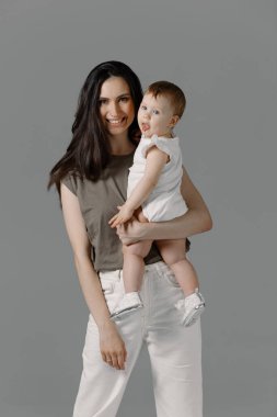 Açık renk elbiseli bir kadın, küçük tatlı bir kızla eğleniyor. Anne, küçük kız pastel bej duvar arkasında izole edilmiş, stüdyo portresi. Anneler Günü aşk ailesi, ebeveynlik çocukluk kavramı