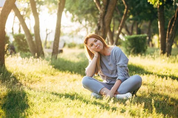 Girl in casual style sitting on the grass in the park