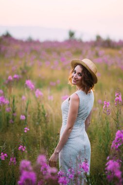 Çiçek tarlasında hasır şapkalı bir kız.