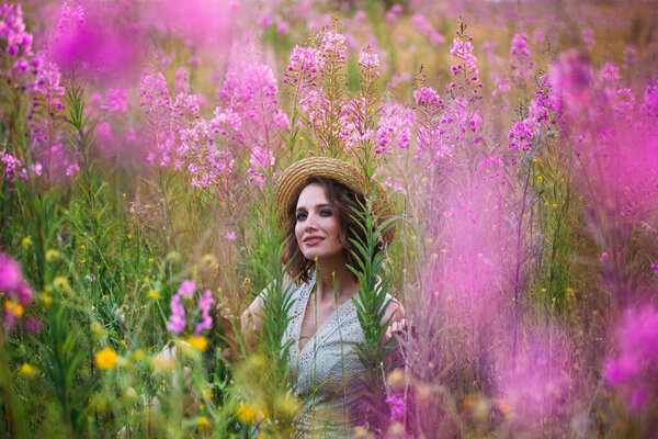 A girl in a straw hat in a field of flowers