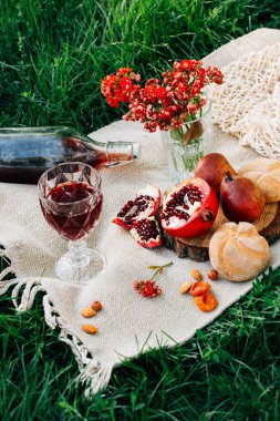 Parkta piknik. Nar, çörekler, armutlar, çiçekler, şarap ve bardaklar