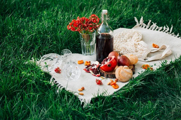 Parkta piknik. Nar, çörekler, armutlar, çiçekler, şarap ve bardaklar