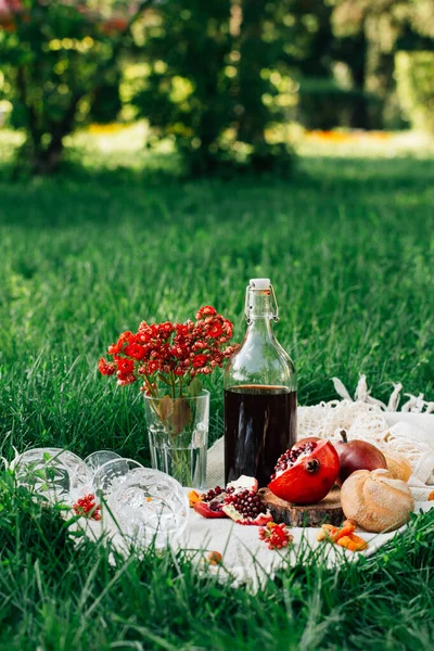 Parkta piknik. Nar, çörekler, armutlar, çiçekler, şarap ve bardaklar