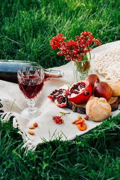 Parkta piknik. Nar, çörekler, armutlar, çiçekler, şarap ve bardaklar