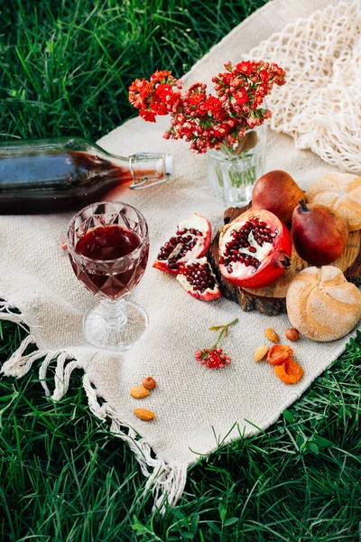 Parkta piknik. Nar, çörekler, armutlar, çiçekler, şarap ve bardaklar