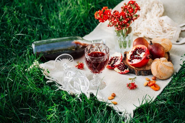 Parkta piknik. Nar, çörekler, armutlar, çiçekler, şarap ve bardaklar