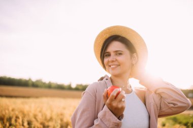 Elmalı tarlada hasır şapkalı bir kız.
