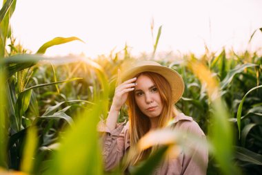 Mısır tarlasında hasır şapkalı bir kız.