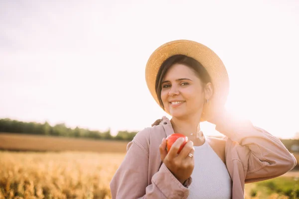 Elmalı tarlada hasır şapkalı bir kız.