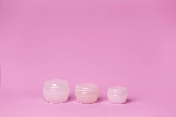 Pembe arka planda kozmetik kavanozları