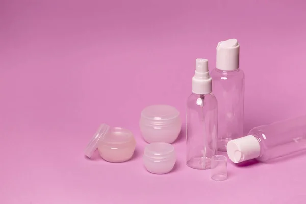 Pembe arka planda kozmetik şişeler ve kavanozlar