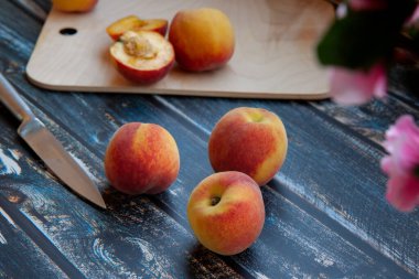 şeftaliler koyu ahşap arka planda, kesme tahtası ve dilimlenmiş şeftali