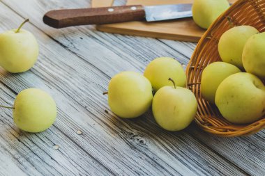 Hafif ahşap arka planda sepetteki yeşil elmalar