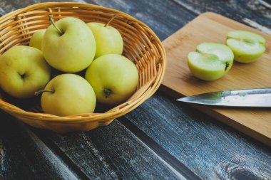Hafif ahşap arka planda sepetteki yeşil elmalar