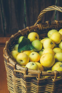 Ahşap bir arka planda örgü sepetinde yeşil elmalar