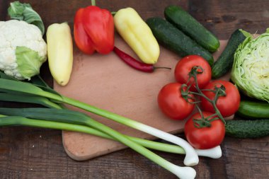 Masanın üzerinde lahana, soğan biberi, salatalık ve domates var..