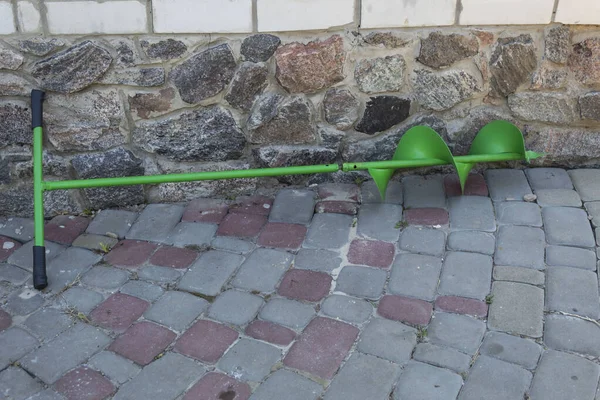 Duvarın yanında, asfalt levhaların üzerinde, delmek için bir el matkabı var..