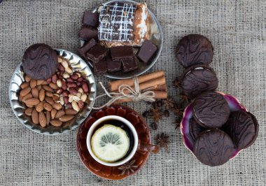 Masada, tabağın üzerinde limonlu bir fincan kahve var ve yanında da bir parça kek, çikolata, kurabiye, kahve çekirdekleri, badem, fıstık, yıldız anason, tarçın çubukları var..