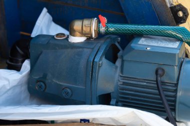 Yakın plan. Harici bir elektrik pompası, yazlık bir evde bitki sulamak için bir kuyudan su sağlar..