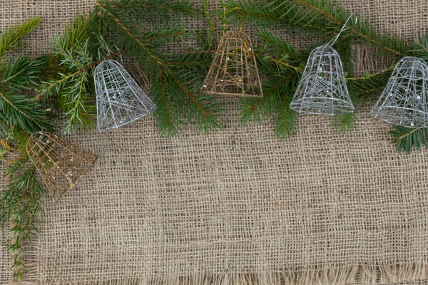Ladin dalları ve beş yeni yıl çanı bir jüt kumaşın üzerinde yatıyor..
