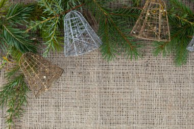 Ladin dalları ve üç yeni yıl çanı jüt kumaşın üzerinde yatıyor..