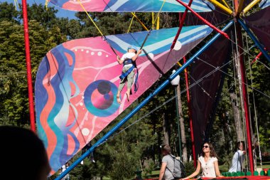 Harkov, Ukrayna. 13 Eylül 2020. Gorky Kültür ve Dinlenme Merkezi Parkı. Parktaki küçük bir çocuk trambolinde zıplıyor. Annem ona gülümserken bakıyor..