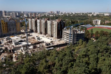 Harkov, Ukrayna. 13 Eylül 2020. Şehrin yukarıdan görünüşü. Ufuk çizgisi, binalar, ağaçlar, bitmemiş evleri olan bir inşaat alanı ve stadyumun yeşil alanı görülebilir durumda.