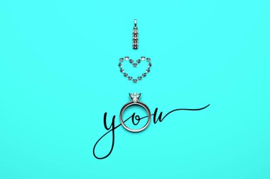 Bir nişan yüzüğü, beyaz altın bir kolye ve turkuaz (Tiffany mavisi) arka planda bulunan kalp şeklinde elmaslar ve seni seviyorum sembolik ifadesini oluşturan kaligrafik bir metin. 3 Boyutlu Hazırlama.