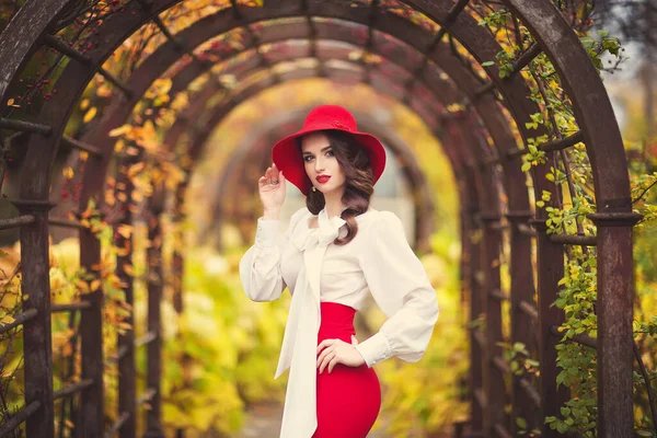 秋の公園を背景に 赤い帽子 白いブラウス 赤いスカートに身を包んだ美しい少女 — ストック写真