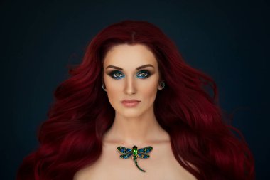 Parlak yeşil makyajlı ve boynunda yusufçuk broşu olan güzel kızıl saçlı bir kızın portresi..