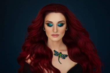 Parlak yeşil makyajlı ve boynunda yusufçuk broşu olan güzel kızıl saçlı bir kızın portresi..