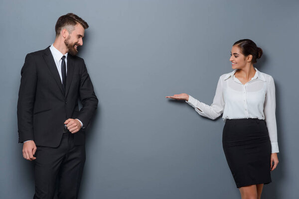 Woman shows something abstract to her business partner. Copy space between two businesspersons dressed following strict dresscode.