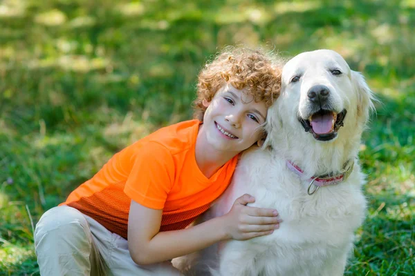 Sorridente ragazzo abbraccia il suo cane — Foto Stock