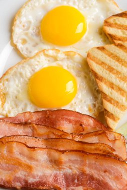 İştah açıcı kavrulmuş domuz pastırması şeritler, tost ve kızarmış yumurta, yakın çekim. Dikey görüntü. Ev yapımı yemek.