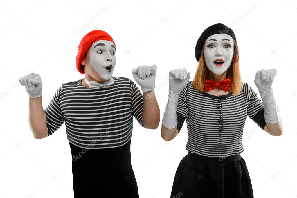 Couple of mimes on white, looking out of imaginary wall. A pantomime sketch of man and woman, dressed in striped shirts, bow ties and hats.