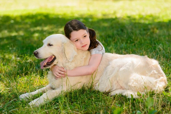 Задумчивый ребенок обнимает собаку — стоковое фото