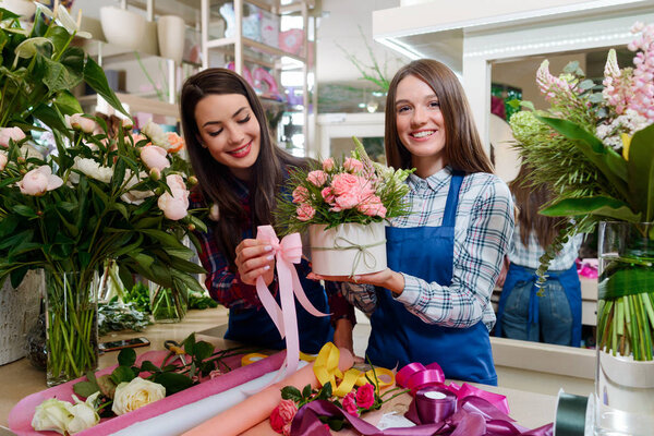 Два флориста создают подарок на день рождения. Великолепная комбинация роз, люпин и травы в коробке, украшенной бабочкой
.