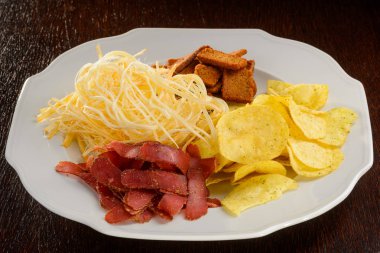 Beyaz bir plaka üzerinde çeşitli atıştırmalıklar. Harika set ve bira severler için büyük ürün çeşitliliği: gevrek cipsi ve Peksimet, chewy sarsıntılı ve lezzetli füme peynir.