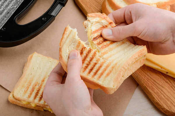 Hands tearing a hot sandwich
