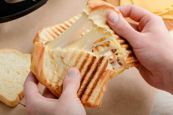 Hands tearing a sandwich