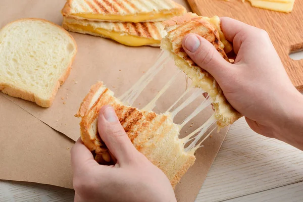 Man tearing a grilled sandwich