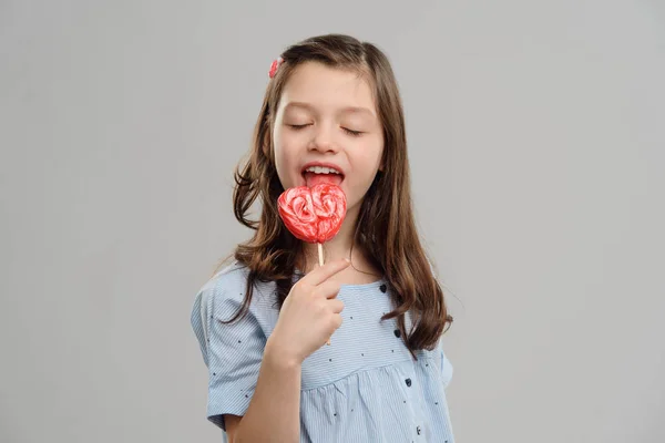 Meisje likken hartvormige lollipop — Stockfoto