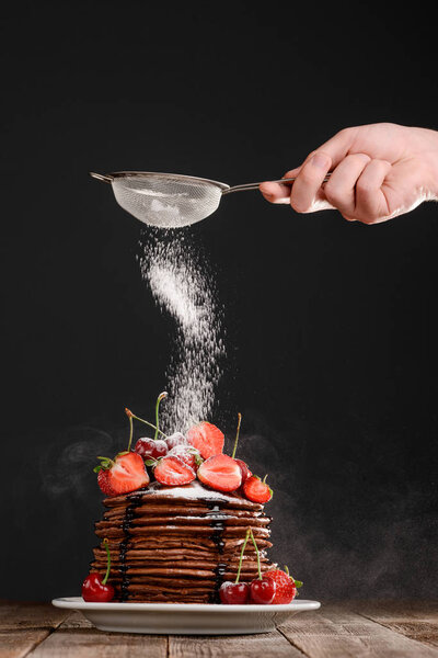 Dusting powdered sugar on dessert