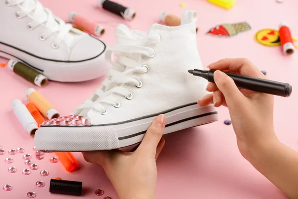 Girl drawing on a sneaker