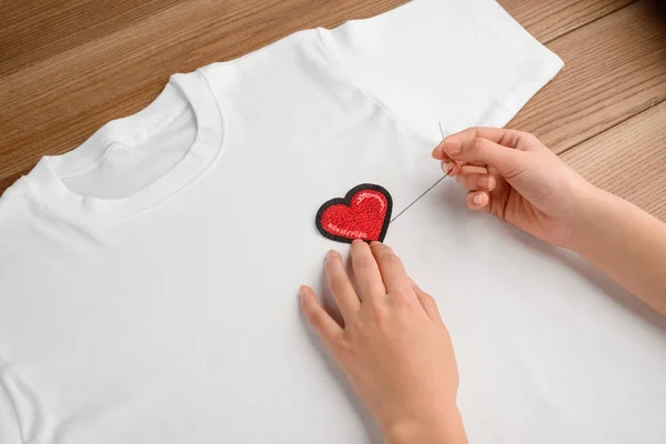 Woman sewing a heart patch — Stock Photo, Image
