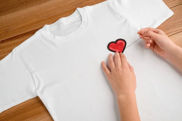 Girl applying embroidered heart patch — Stock Photo, Image