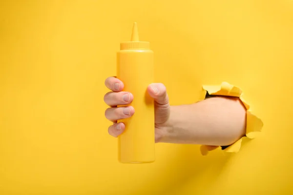 Mão segurando uma garrafa de mostarda — Fotografia de Stock