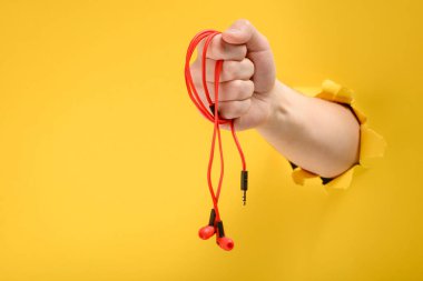 Kırmızı kulak içi kulaklıklar tutan el